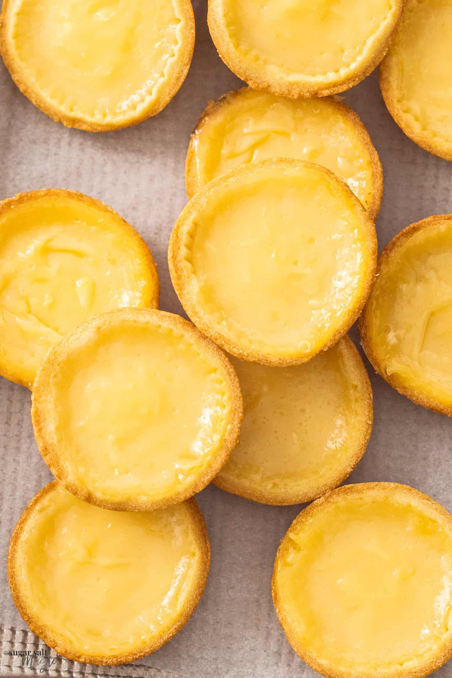 Closeup of lemon tarts on a gold baking tray.