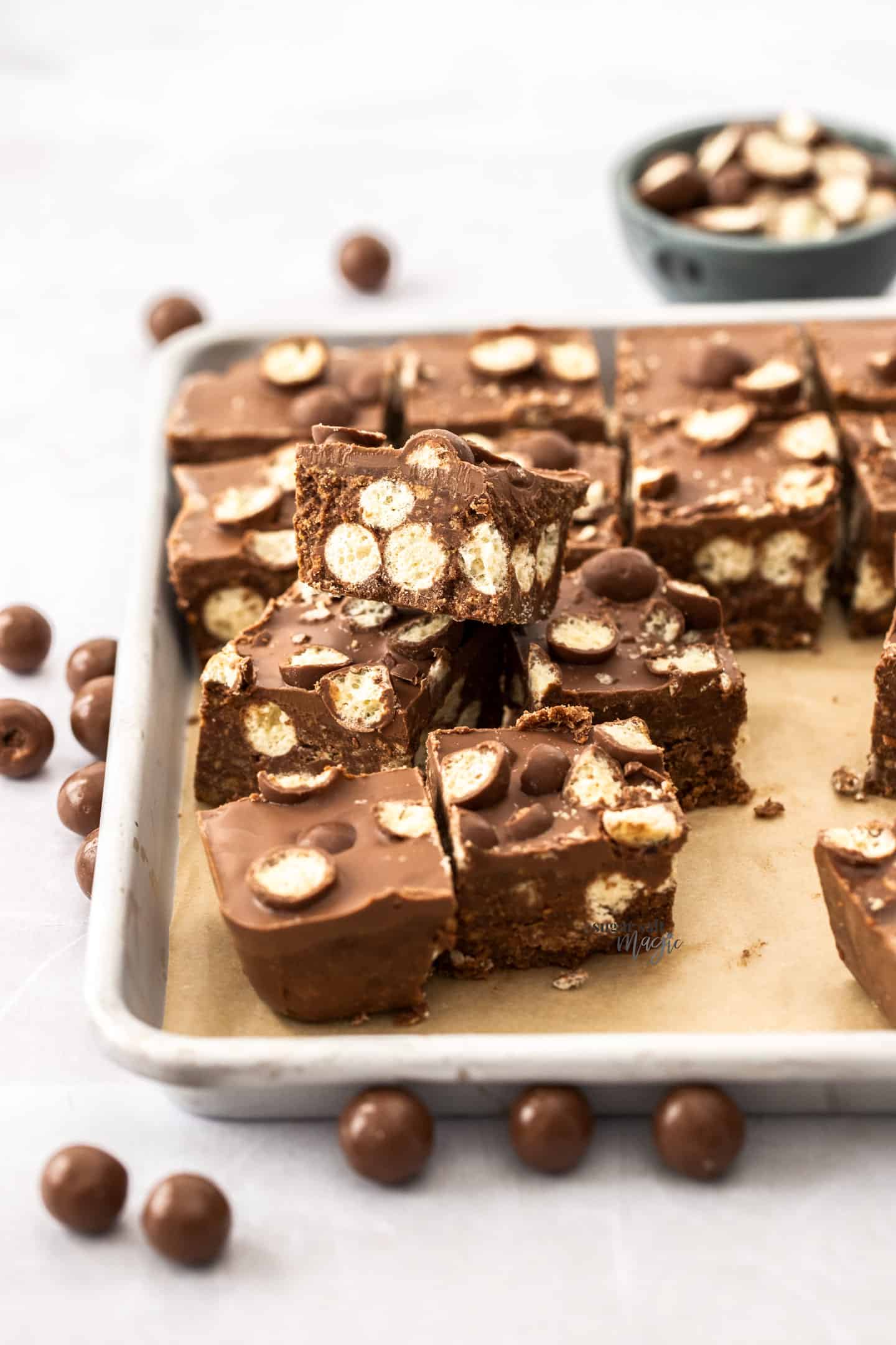 Squares of Maltesers traybake stacked on top of one another showing the side view.