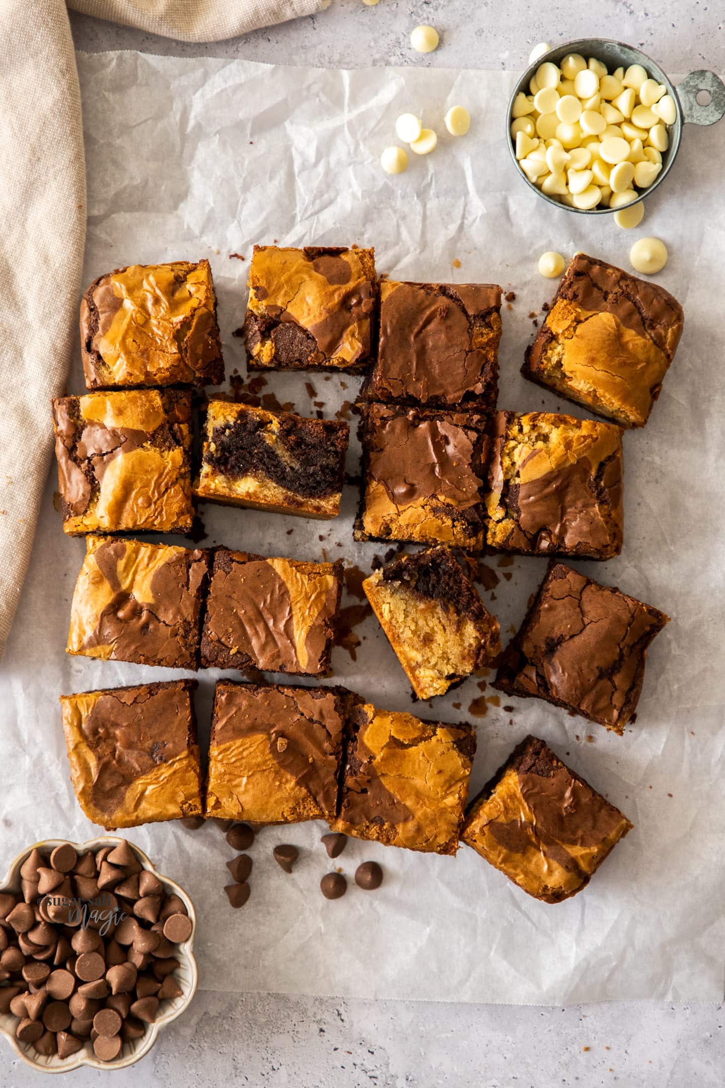 A batch of brownie blondies, cut into squares, surrounded by chocolate chips.