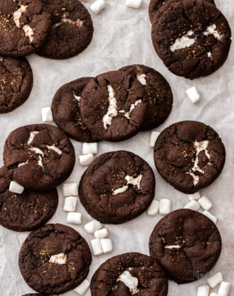 A batch of chocolate marshmallow cookies on a sheet of baking paper.