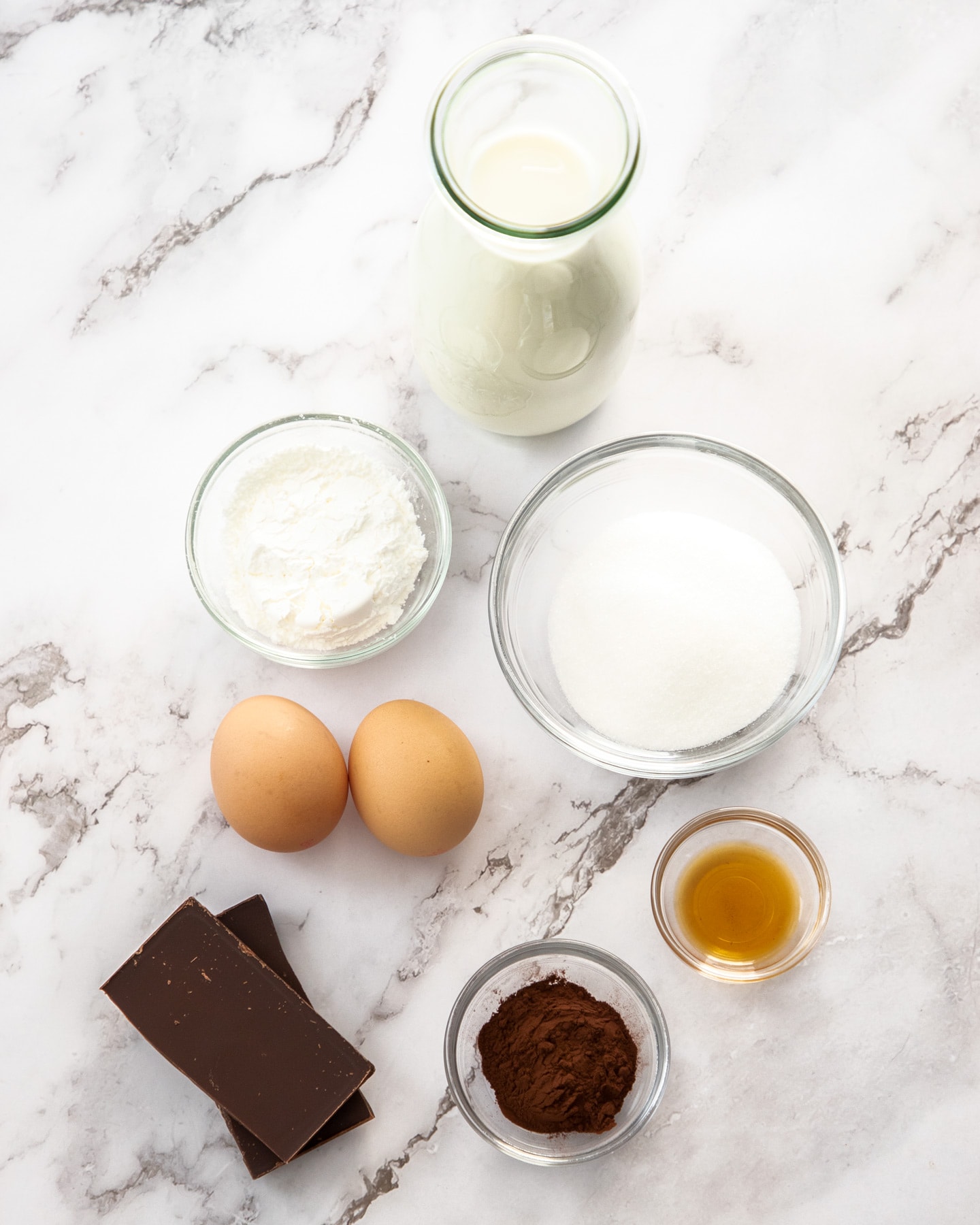 Ingredients for chocolate pastry cream on a marble surface.
