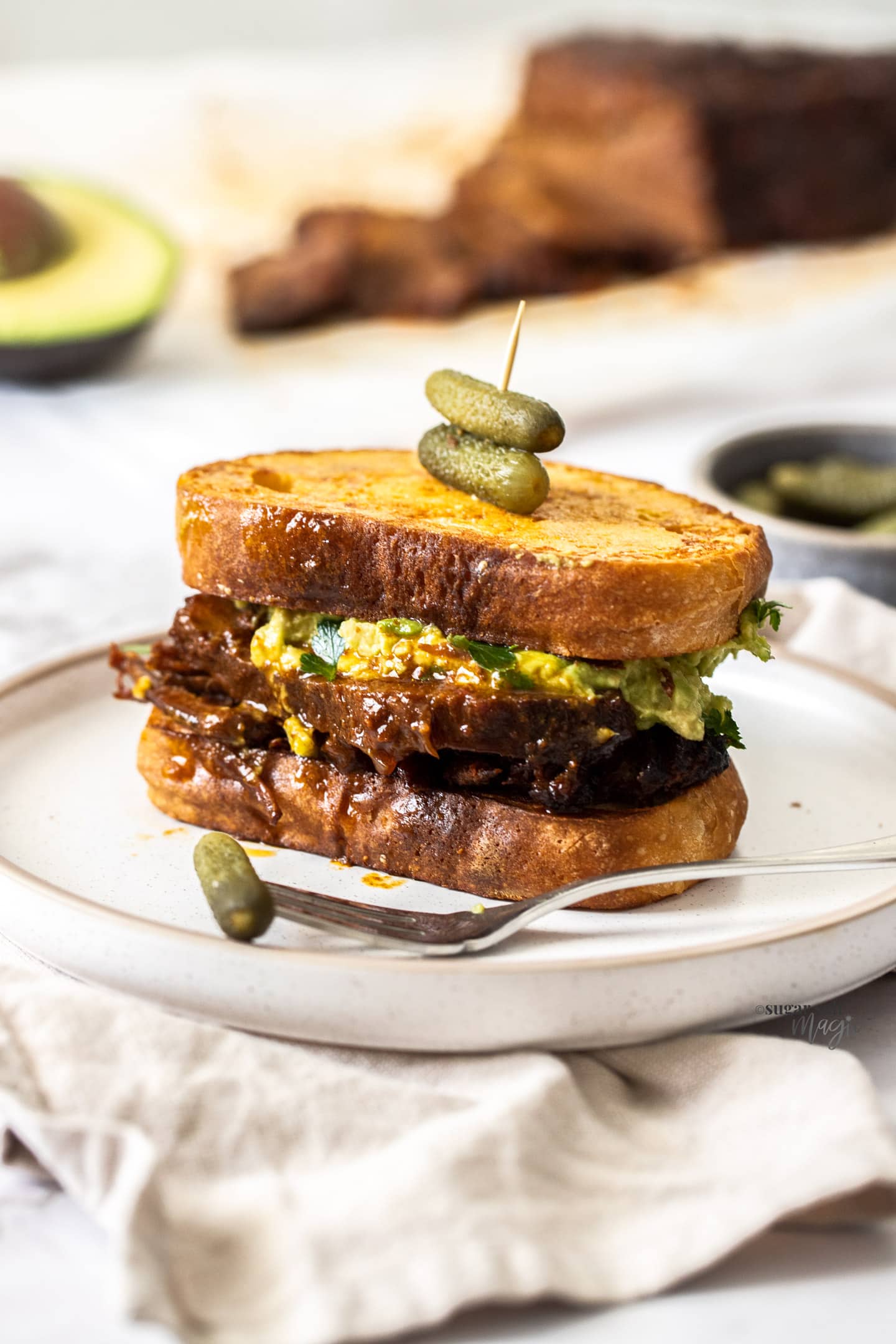 A sandwich filled with BBQ beef brisket slices and avocado.