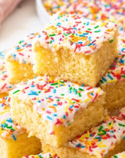 A stack of squares of sponge tray bake topped with sprinkles.