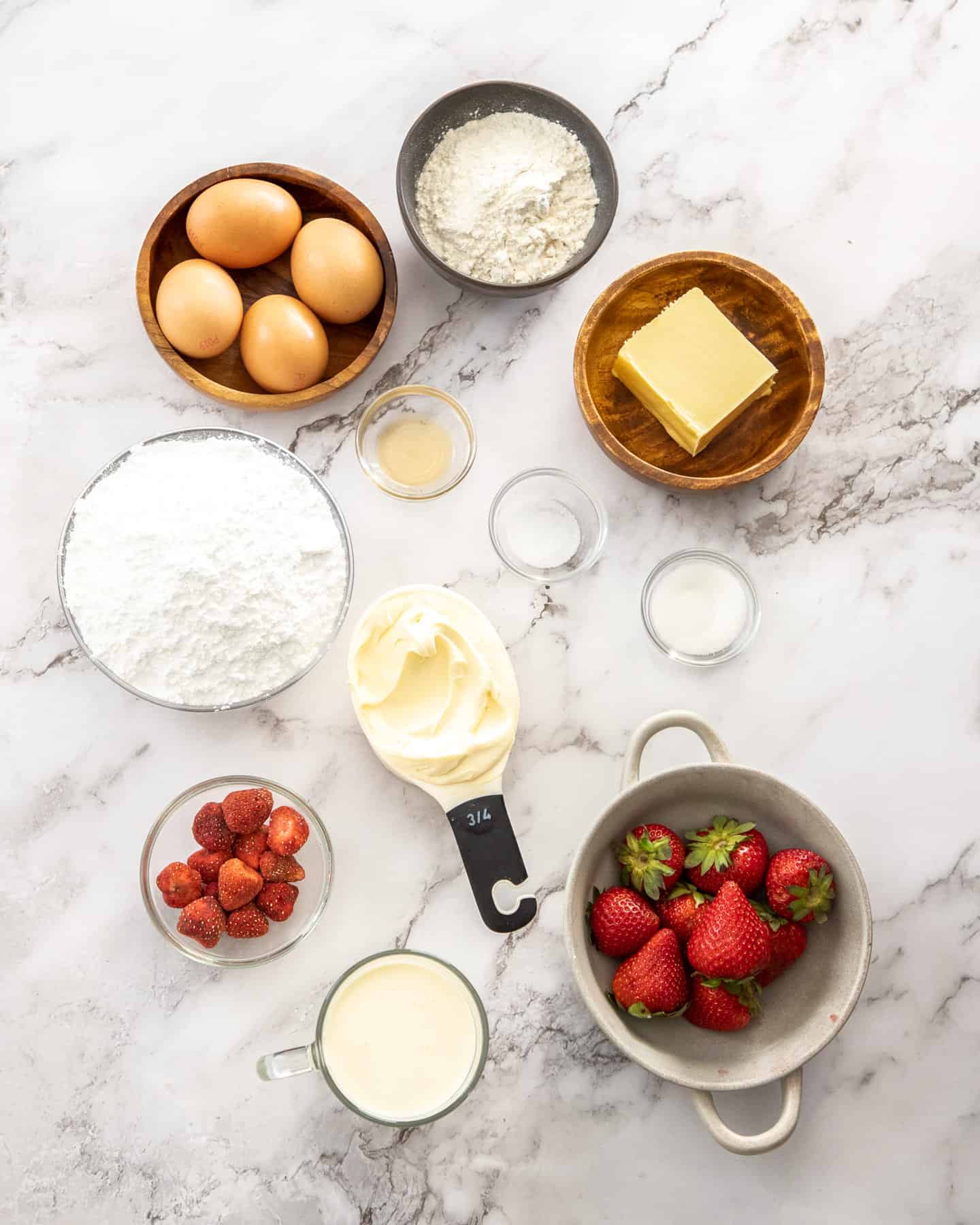 Ingredients for strawberry cream puffs on a marble benchtop.