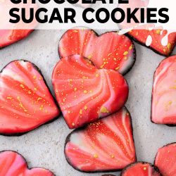 A pile of heart shaped iced sugar cookies on a stone surface.