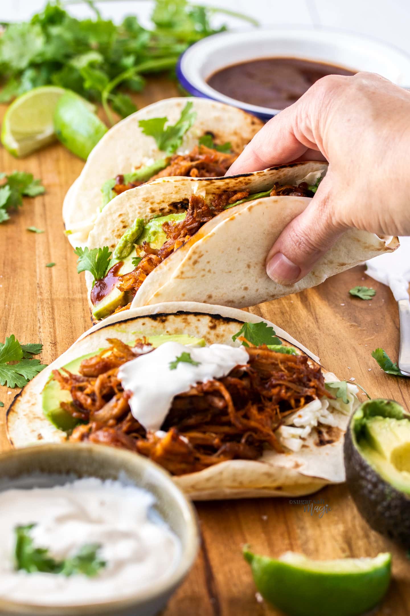 A hand reaching in to pick up a pulled pork taco.