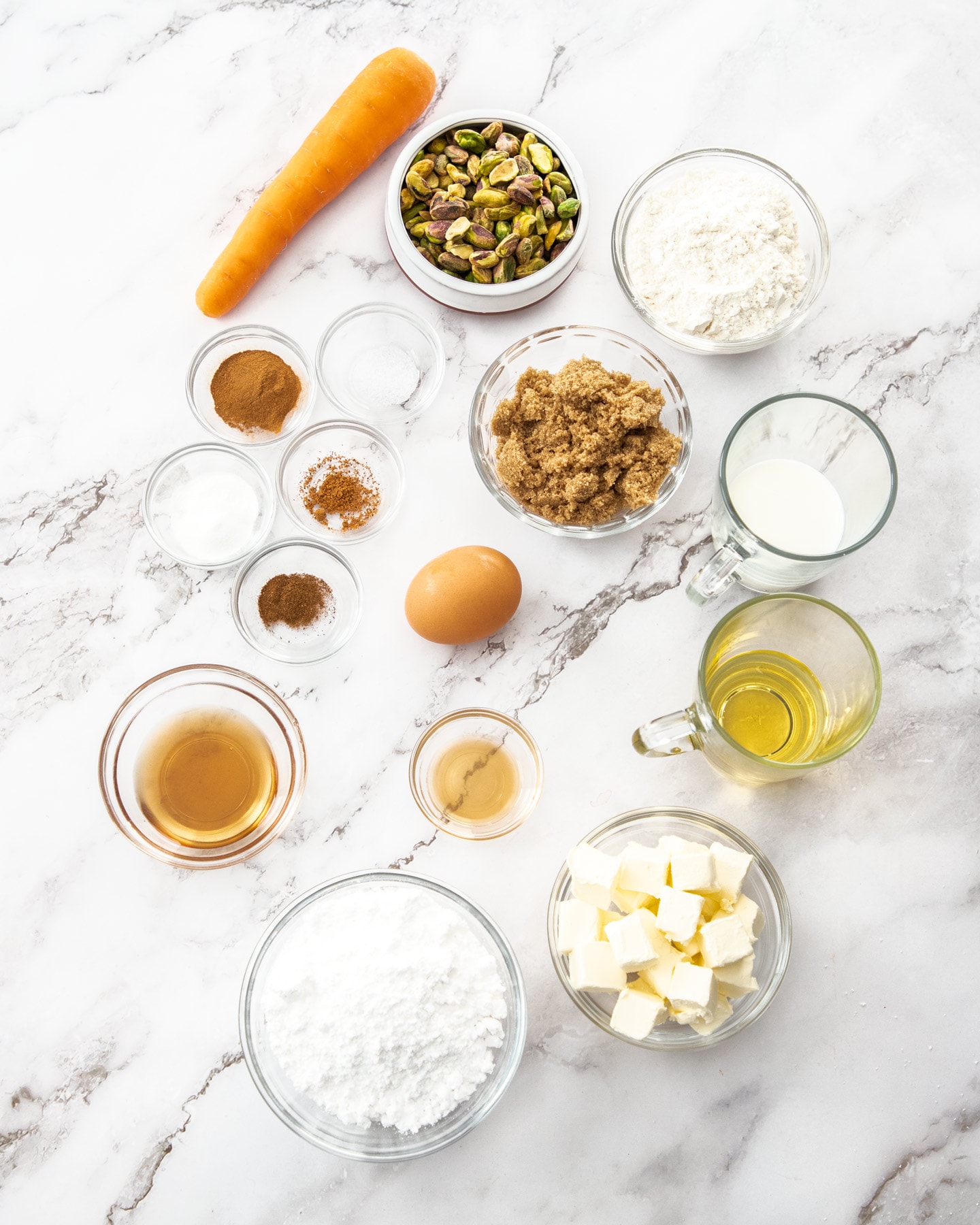 Ingredients for carrot cake donuts on a marble surface.