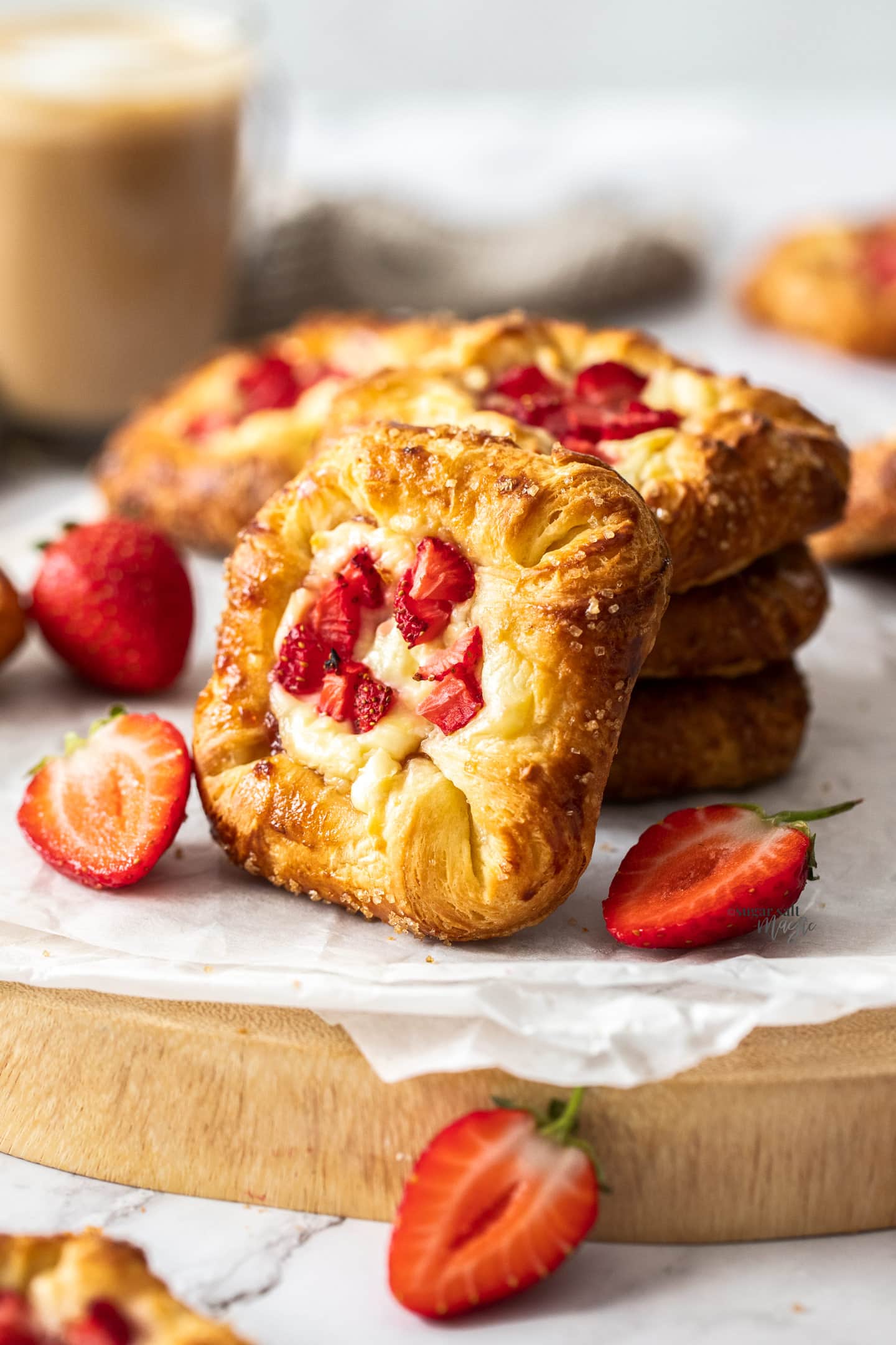 A stack of 3 strawberry Danishes with one leaning up against them.