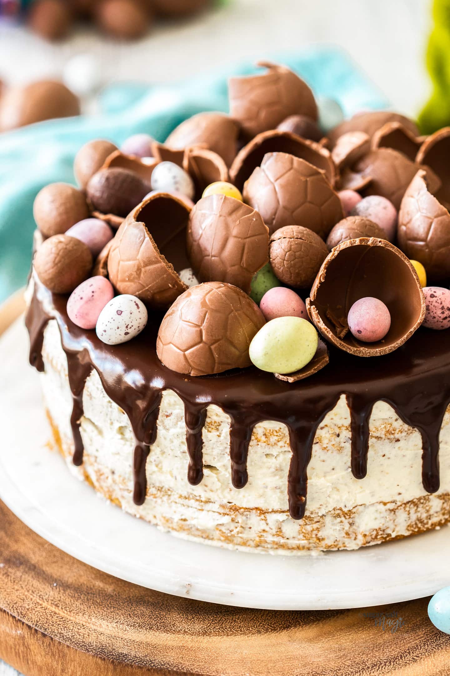 A cake on a cake platter topped with loads of easter eggs.