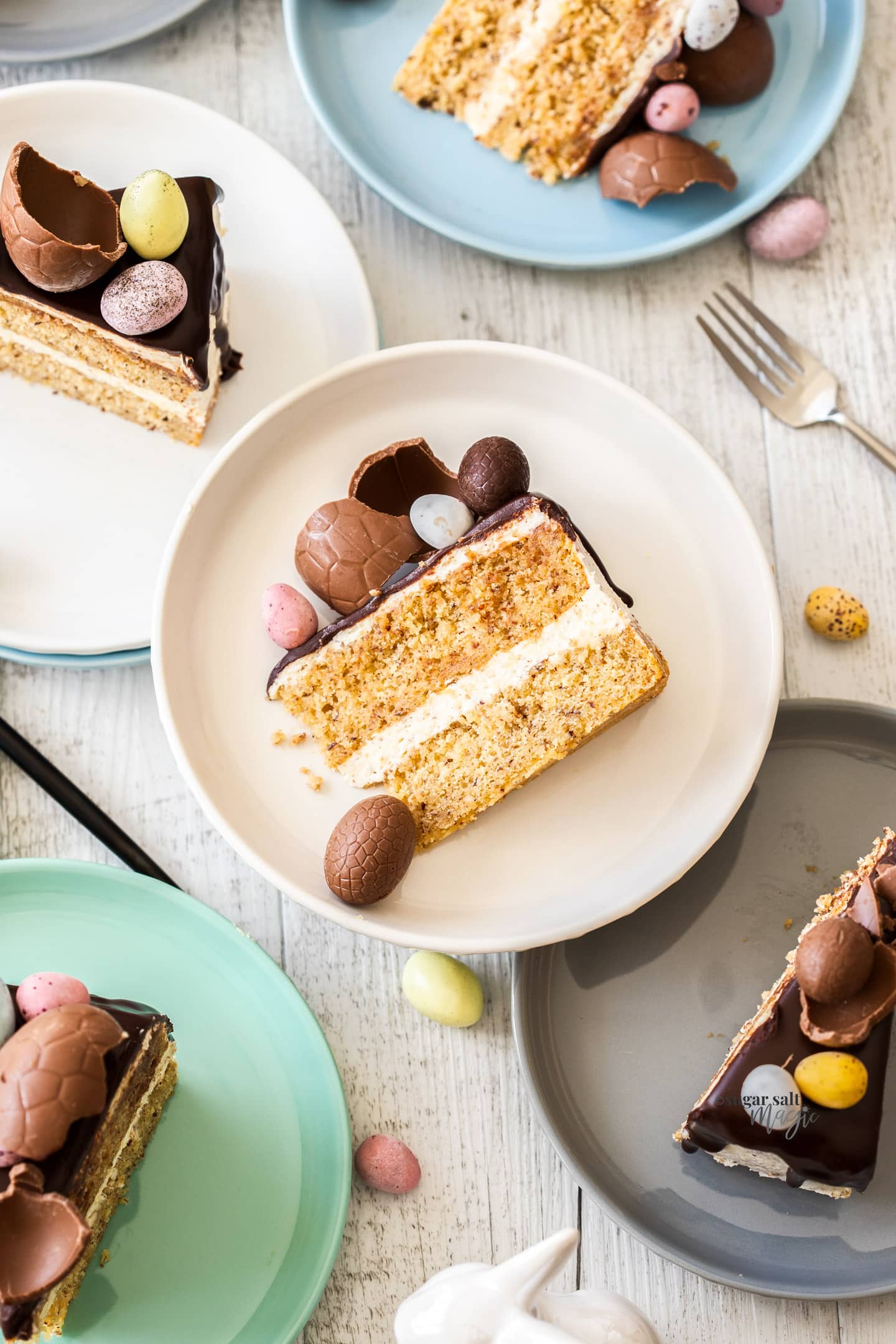 Slices of cake with Easter eggs on top on colourful plates.