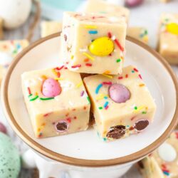 Close up of 3 squares of mini egg fudge on a plate with a gold rim.
