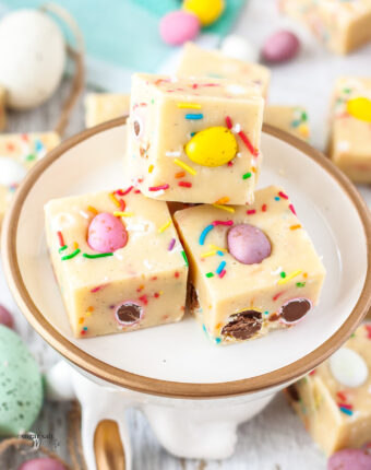 Close up of 3 squares of mini egg fudge on a plate with a gold rim.