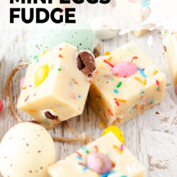 Little squares of mini egg fudge on a white wooden surface.