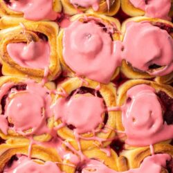 Close up of a tray of 12 raspberry rolls.