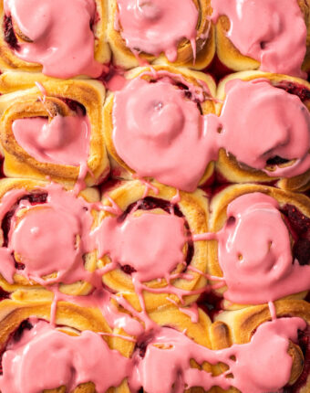 Close up of a tray of 12 raspberry rolls.