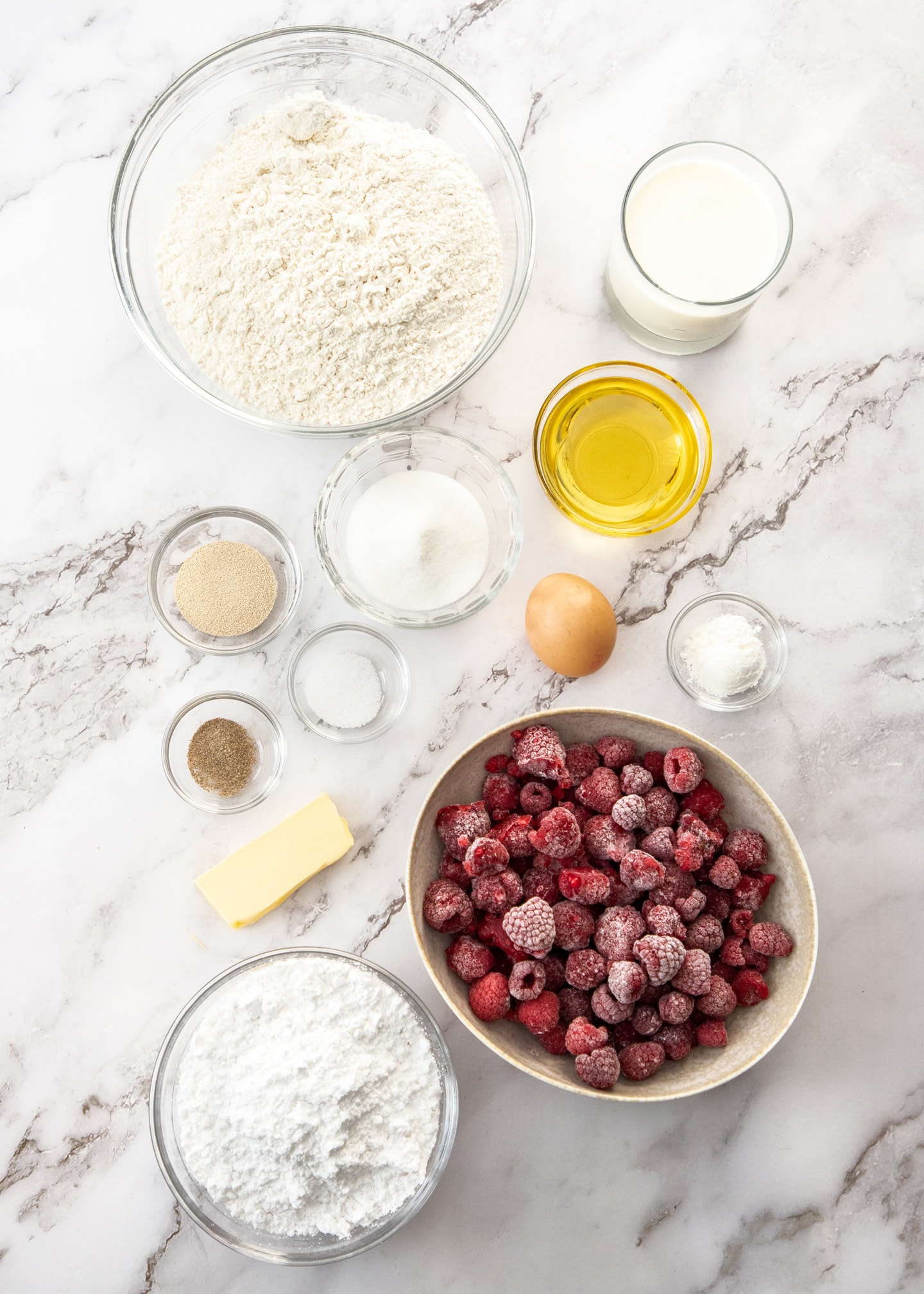 Ingredients for raspberry sweet rolls on a marble surface.