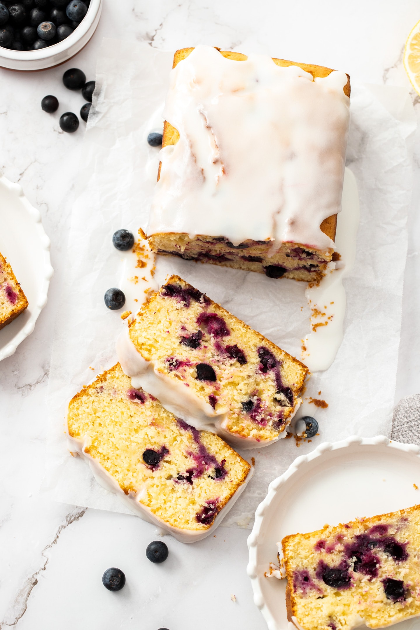 Top down view of a blueberry lemon loaf cake with two slices cut in front of it.