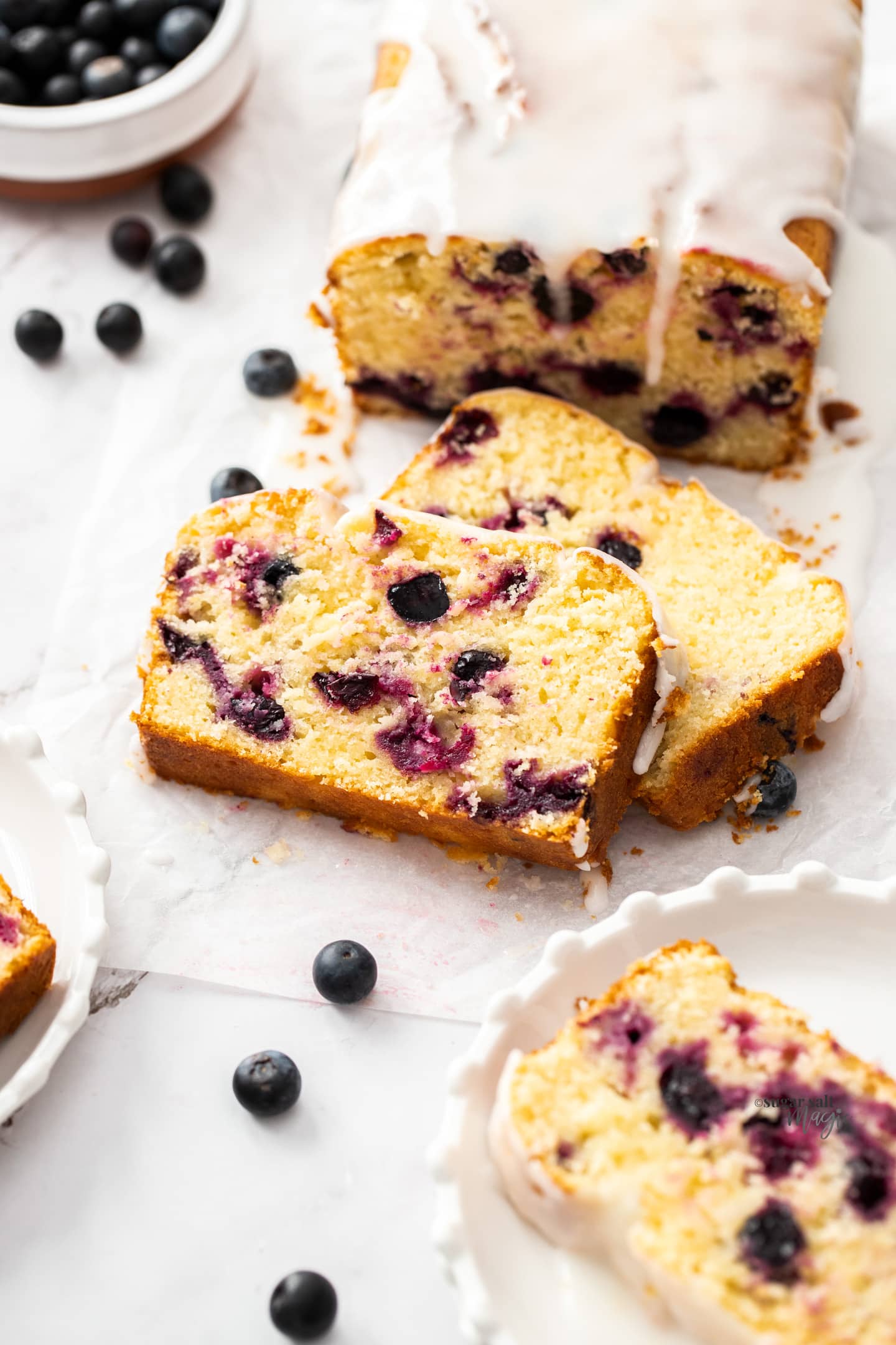 Closeup of two slices of blueberry lemon loaf cake leaning against each other.