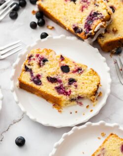 A slice of blueberry lemon loaf cake with a bite taken out.