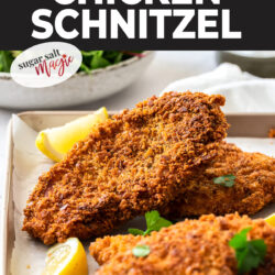 Crunchy, golden chicken schnitzle on a baking tray with lemon wedges.