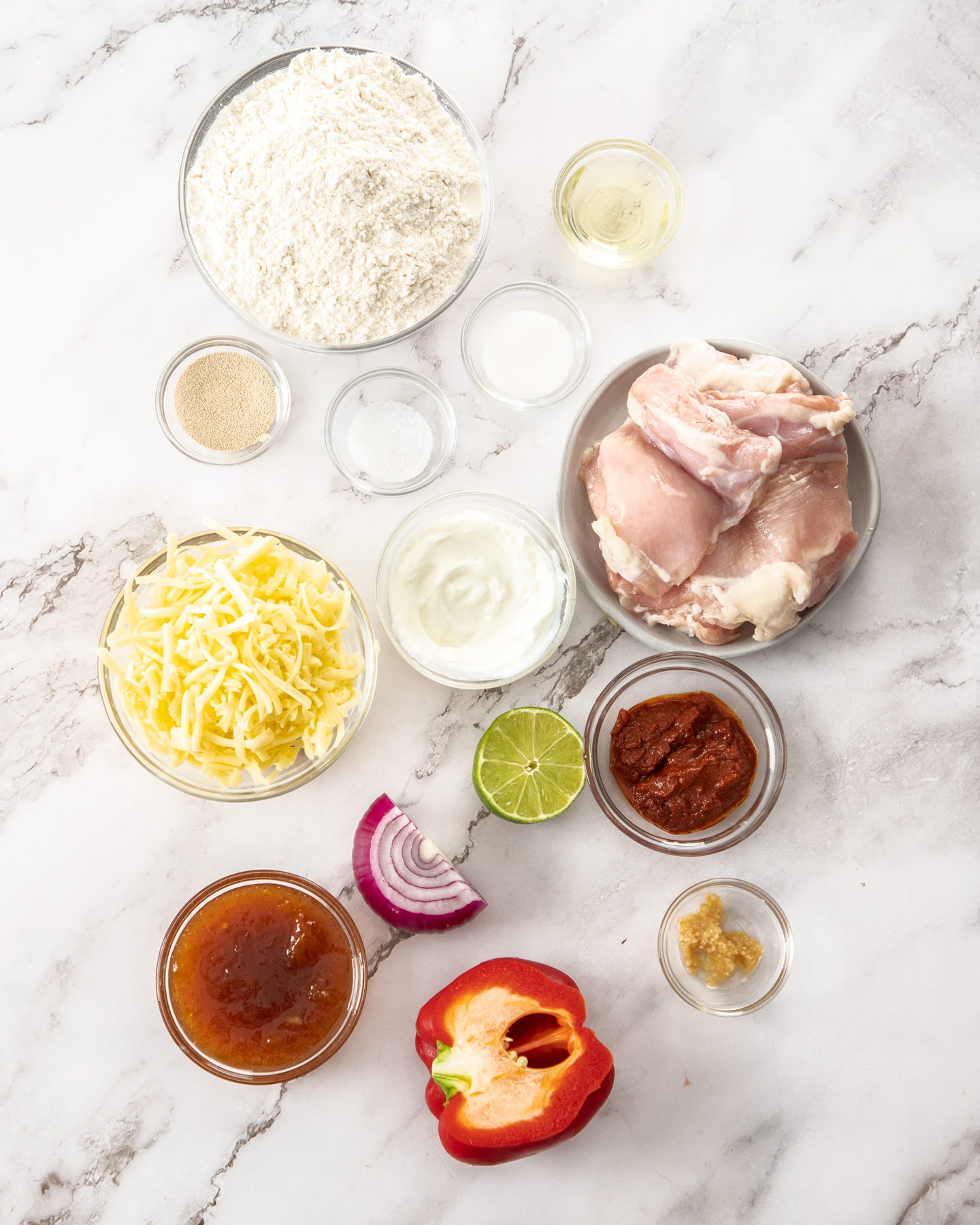 Ingredients for tandoori chicken pizza on a marble surface.
