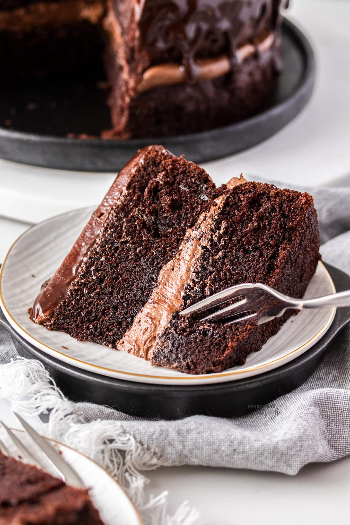 A fork digging into a slice of chocolate cake.
