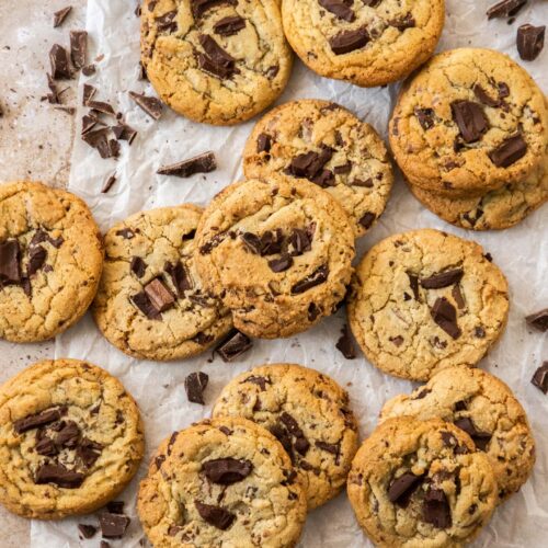 A big batch of chocolate chunk cookies on a sheet of baking paper.