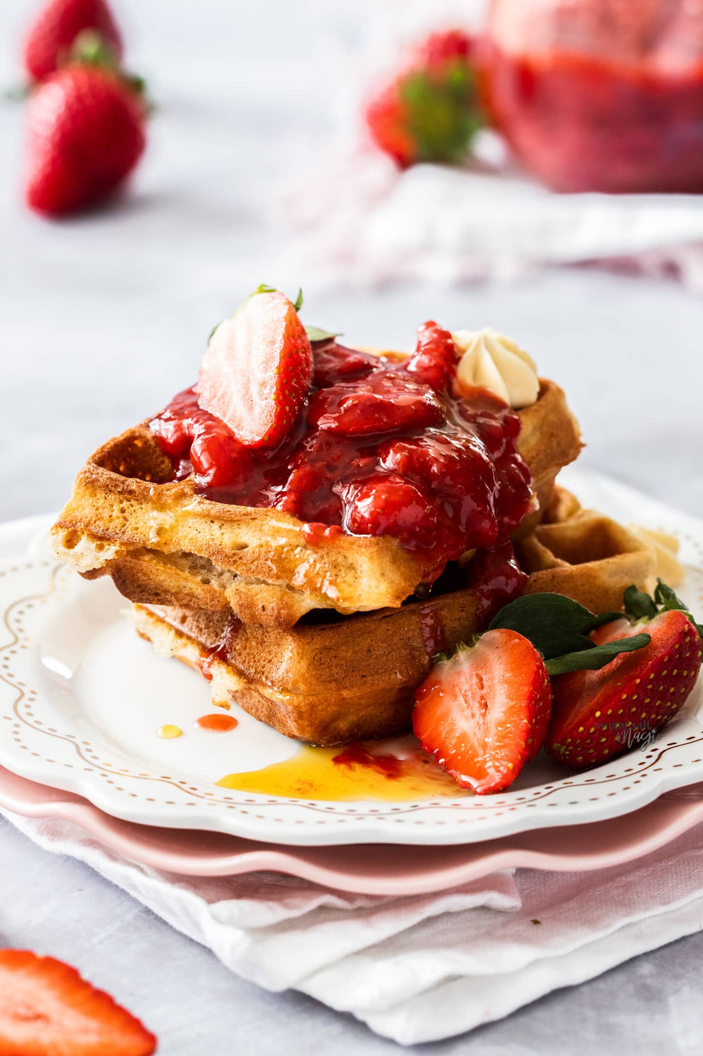 Strawberry topping on two waffles on a dessert plate.