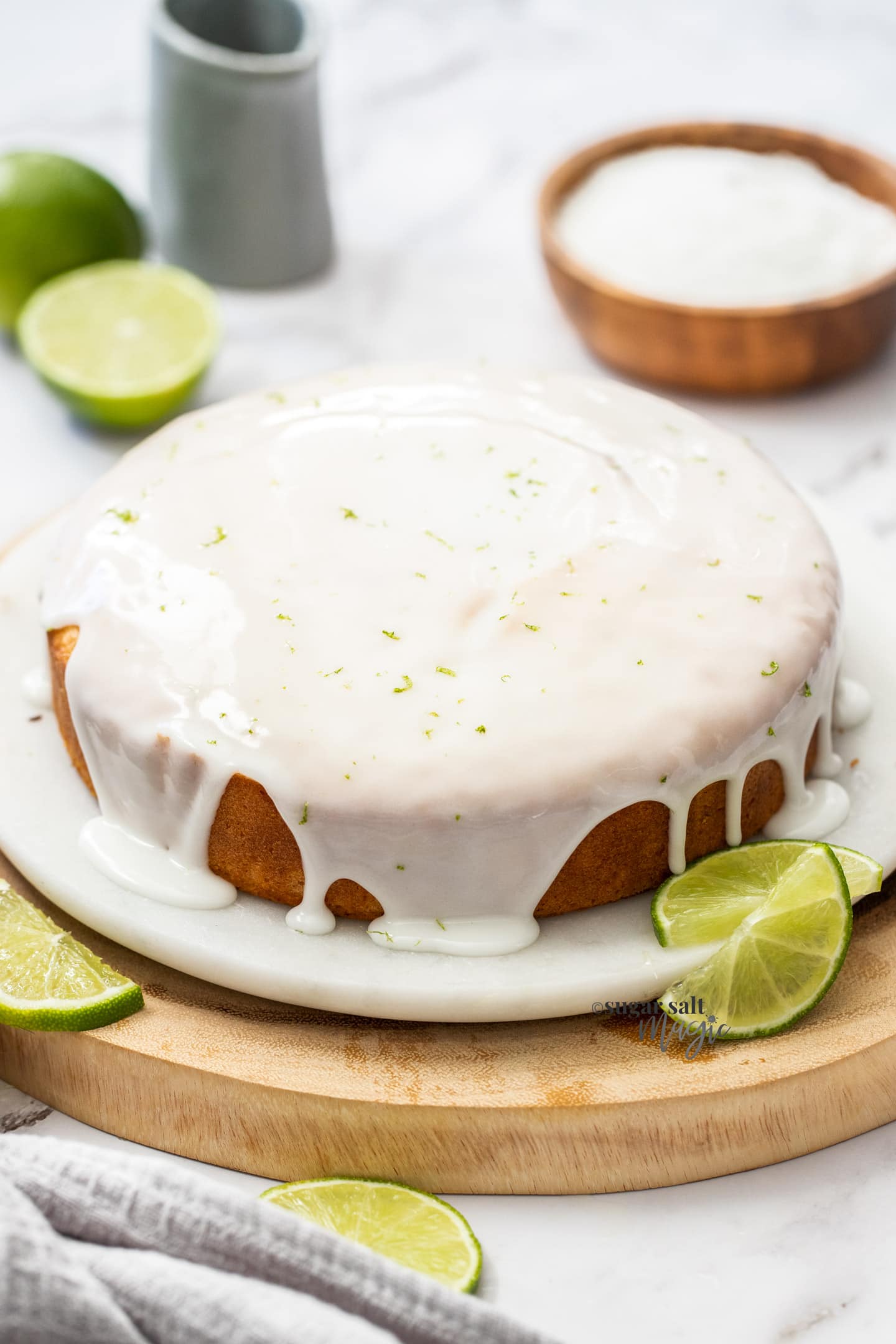 A whole cake covered in lime glaze on a marble cake plate.