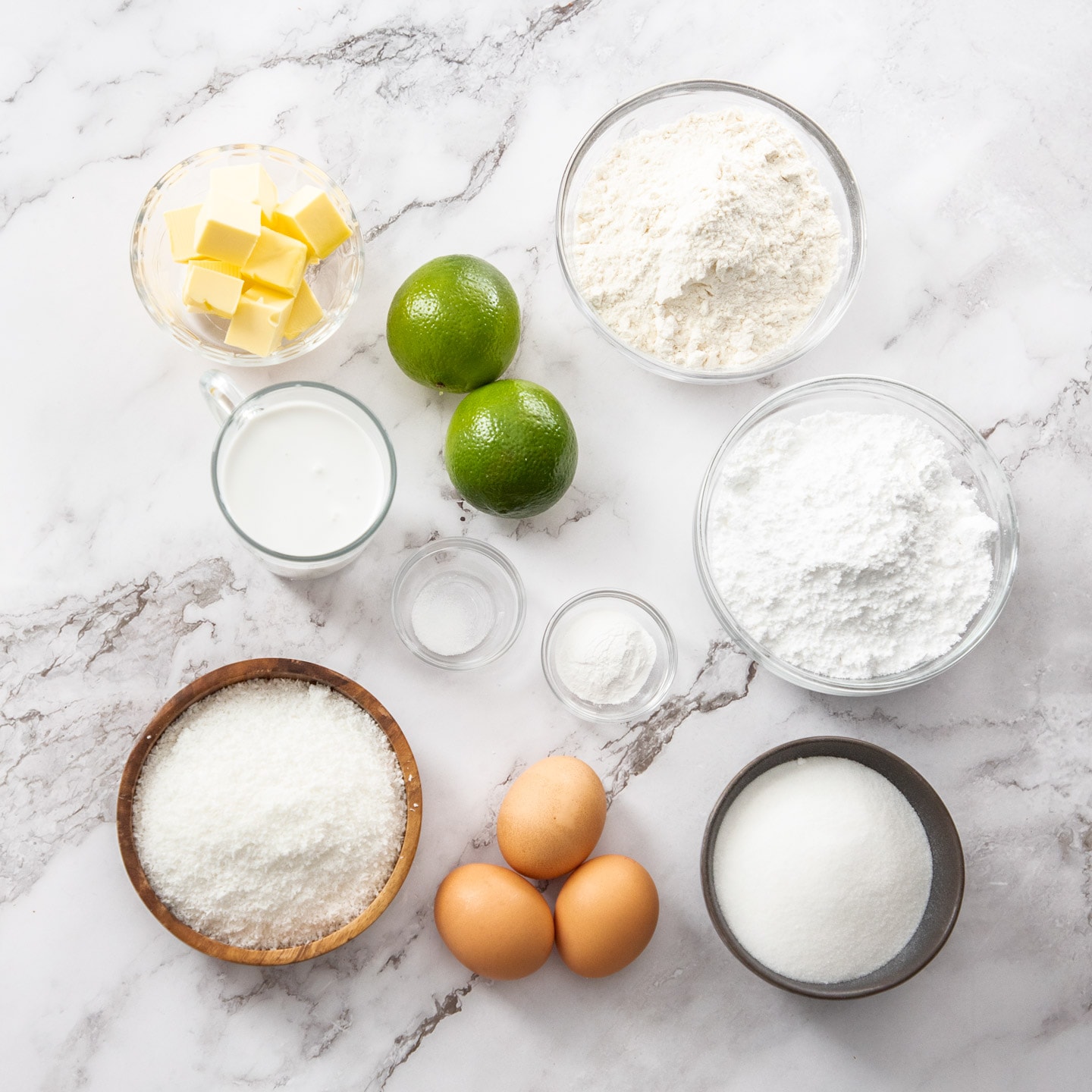 Ingredients for lime and coconut cake on a marble surface.
