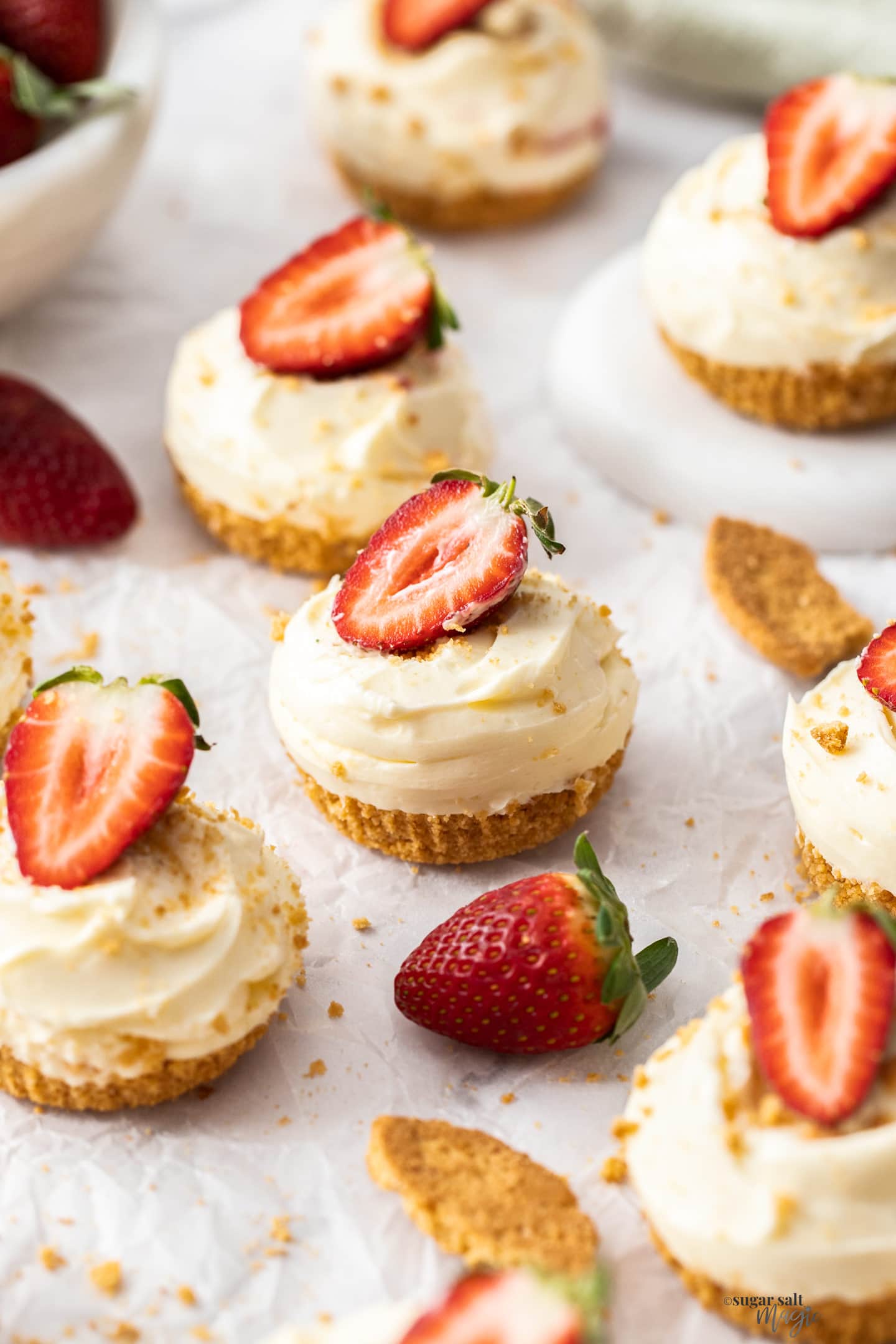 A batch of mini strawberry cheesecakes on a sheet of baking paper.