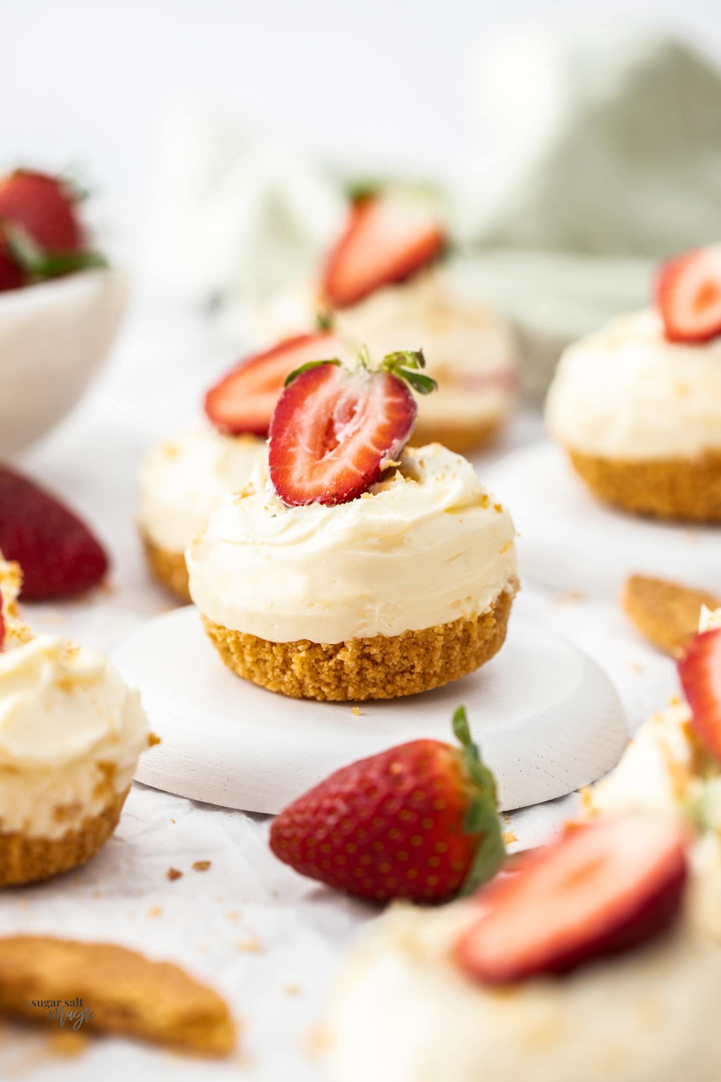 A single mini strawberry cheesecake sitting on a mini dessert plate.