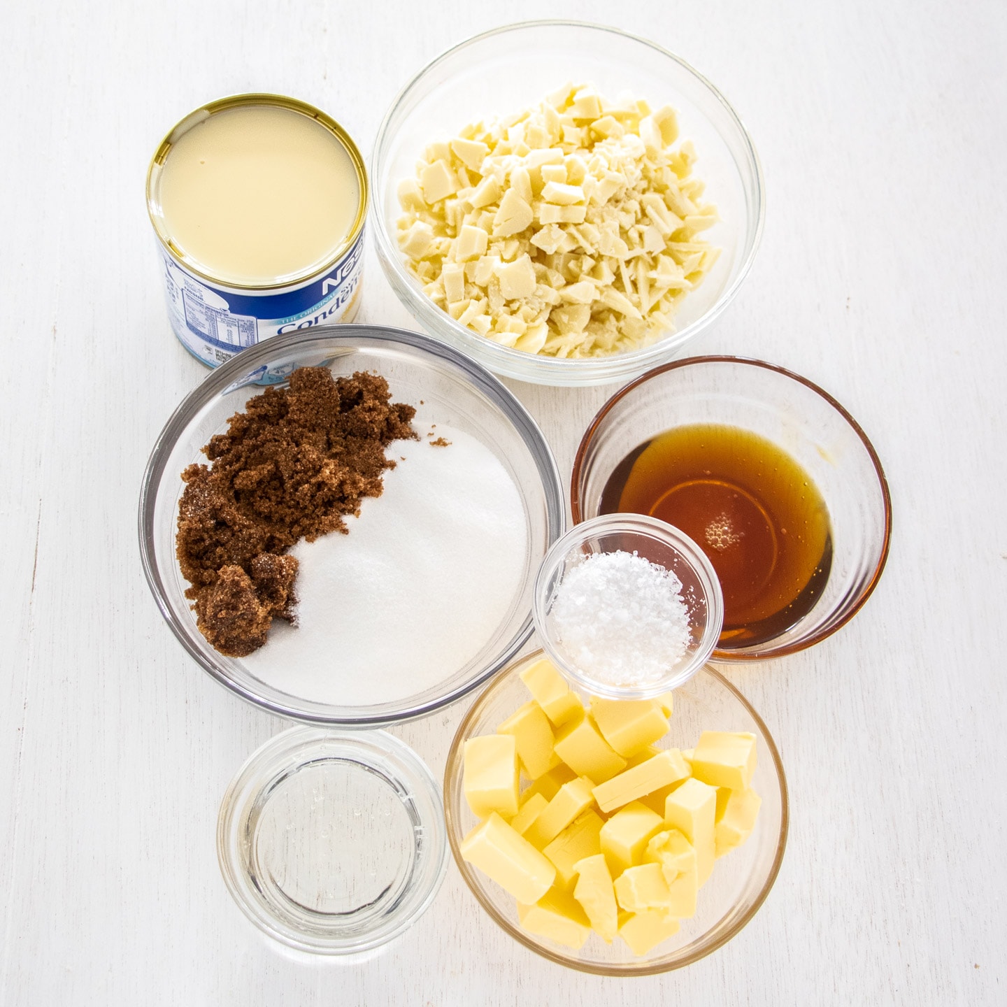 Ingredients for salted caramel fudge on a white wooden bench top.