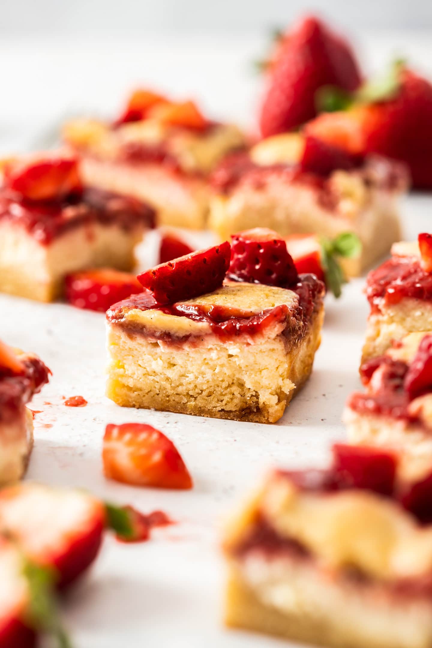 Close up of a strawberry cheesecake bar topped with fresh strawberries.