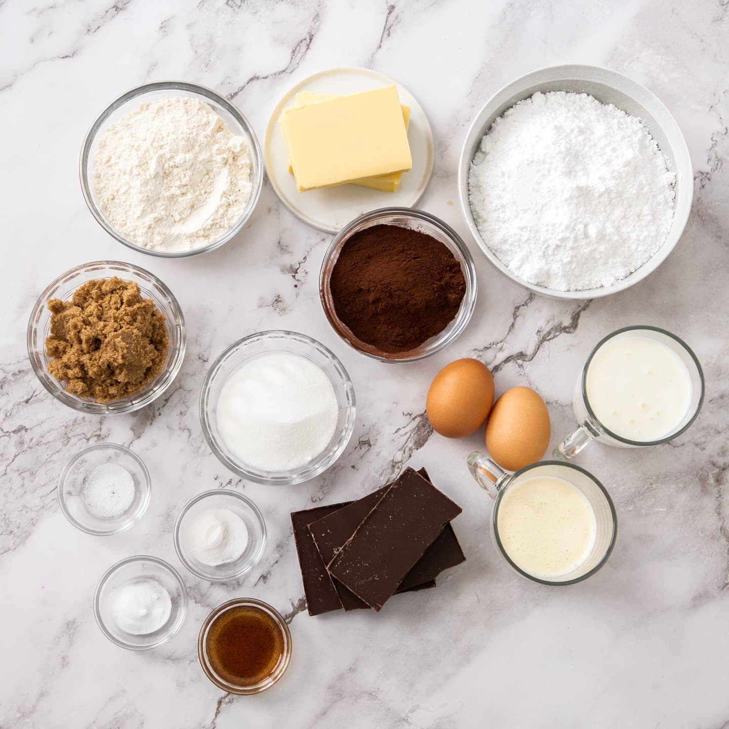 Ingredients for chocolate fudge cupcakes on a marble surface.