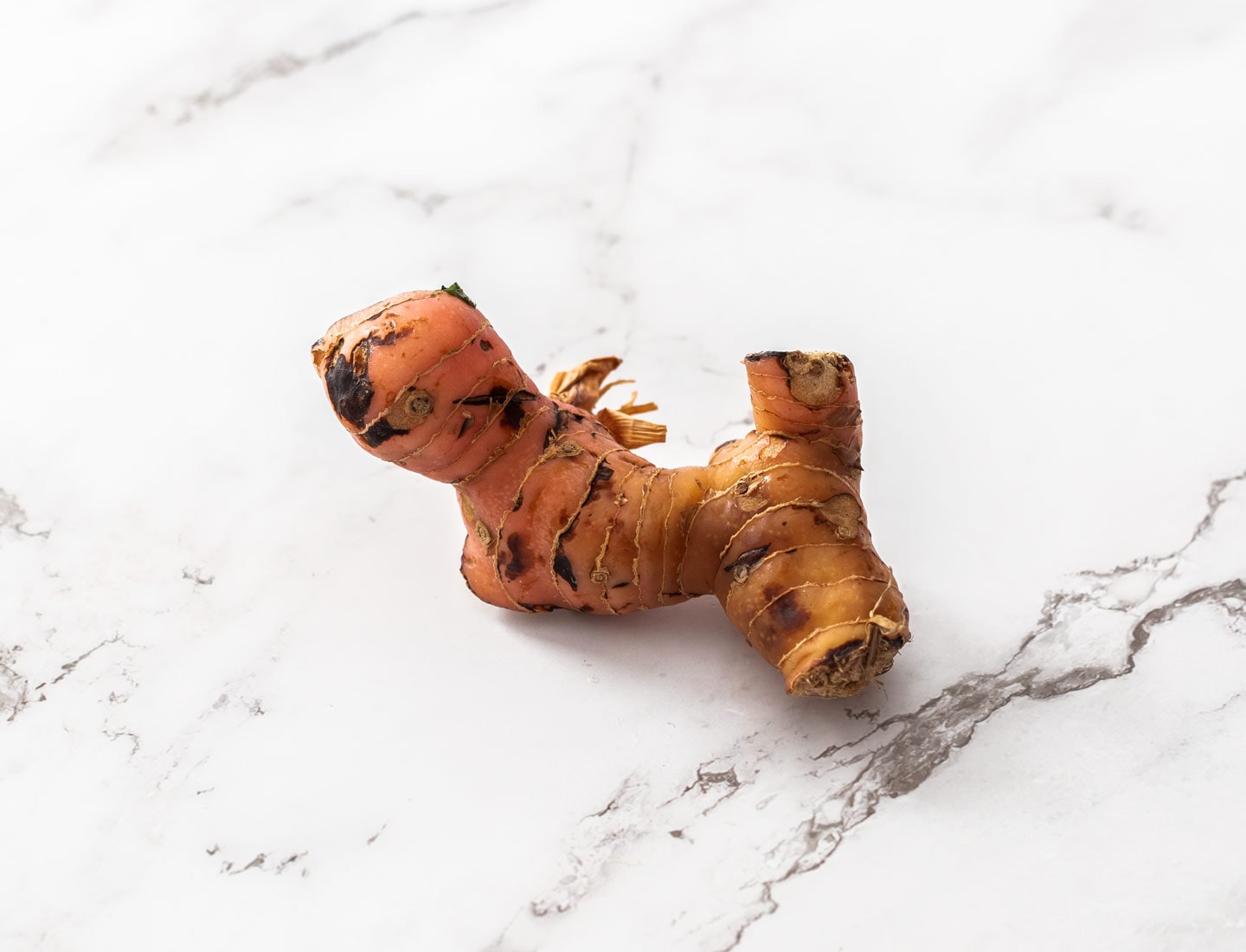 A piece of fresh galangal on a marble benchtop.