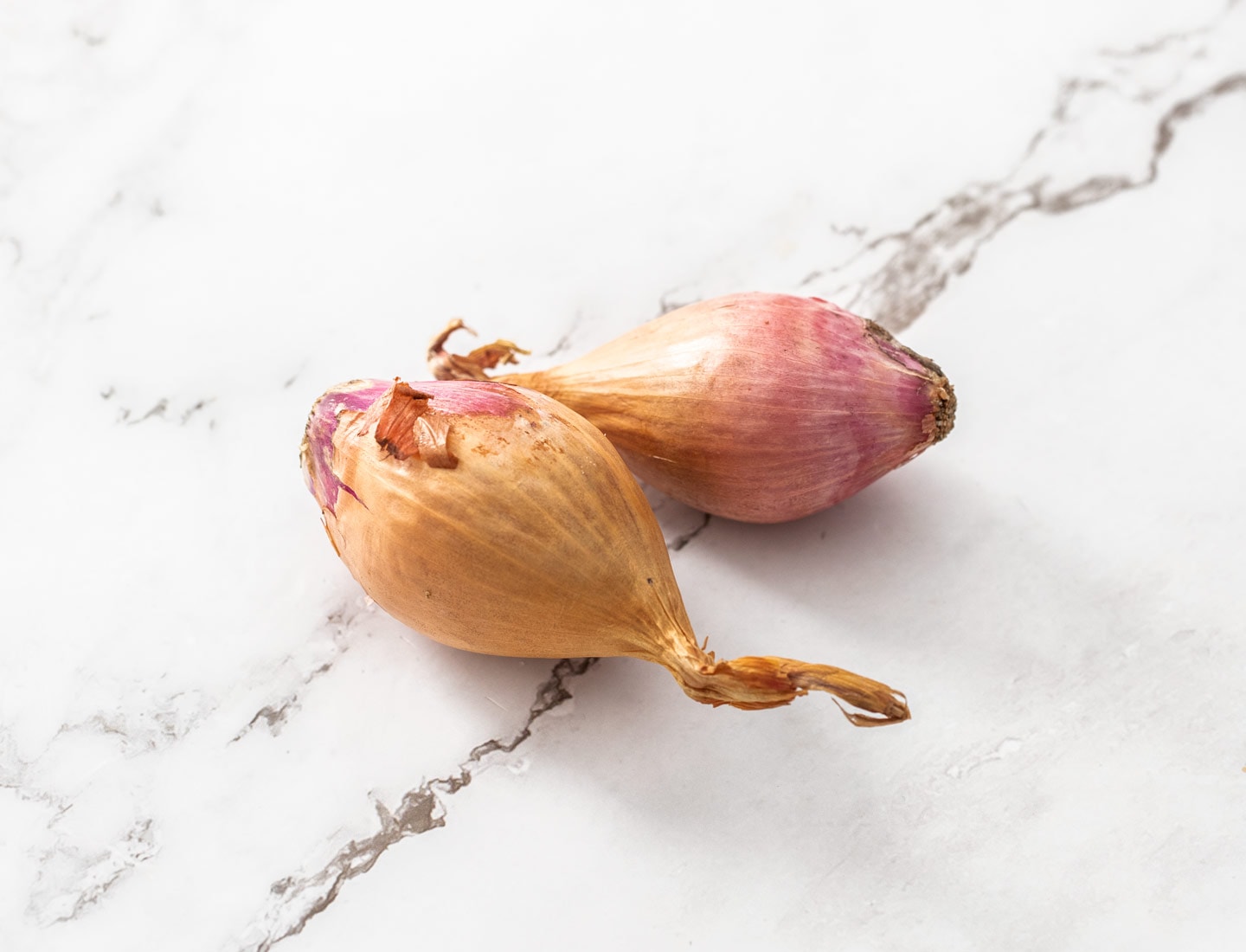 2 shallots on a marble surface.