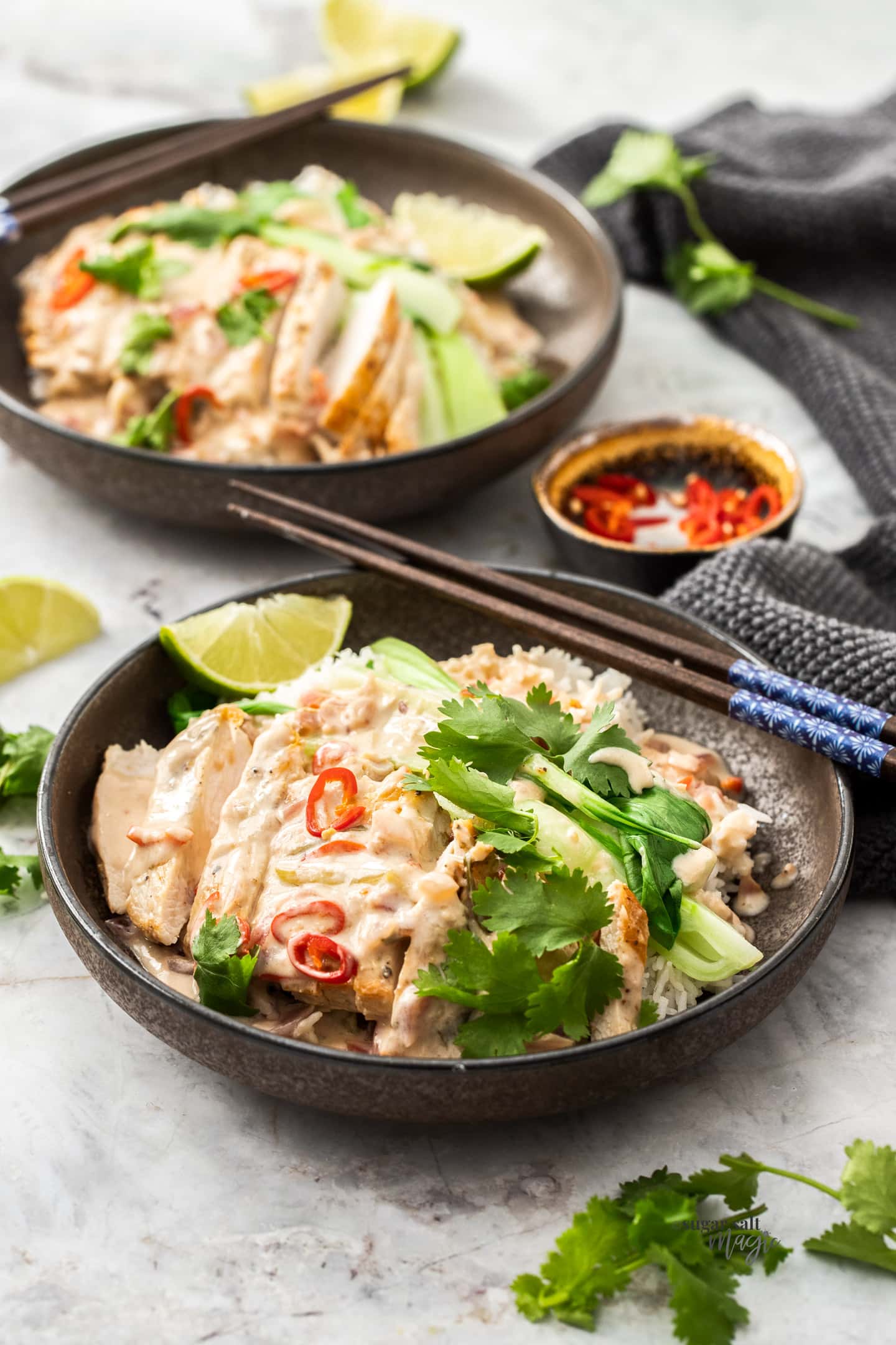 A bowl lime coconut chicken topped with pair of chopsticks.