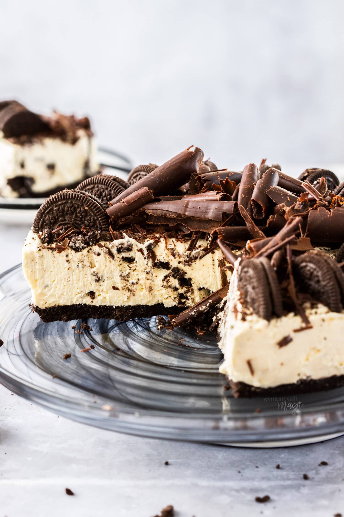 Close up of a cross section of oreo cheesecake topped with oreos and chocolate curls.