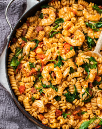 Top down view of prawns in pasta in a large skillet.