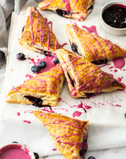 6 puff pastry blueberry turnovers on a sheet of baking paper.