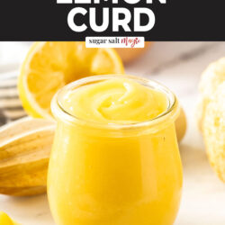 A glass jar filled with lemon curd with a spoon sitting next to it.