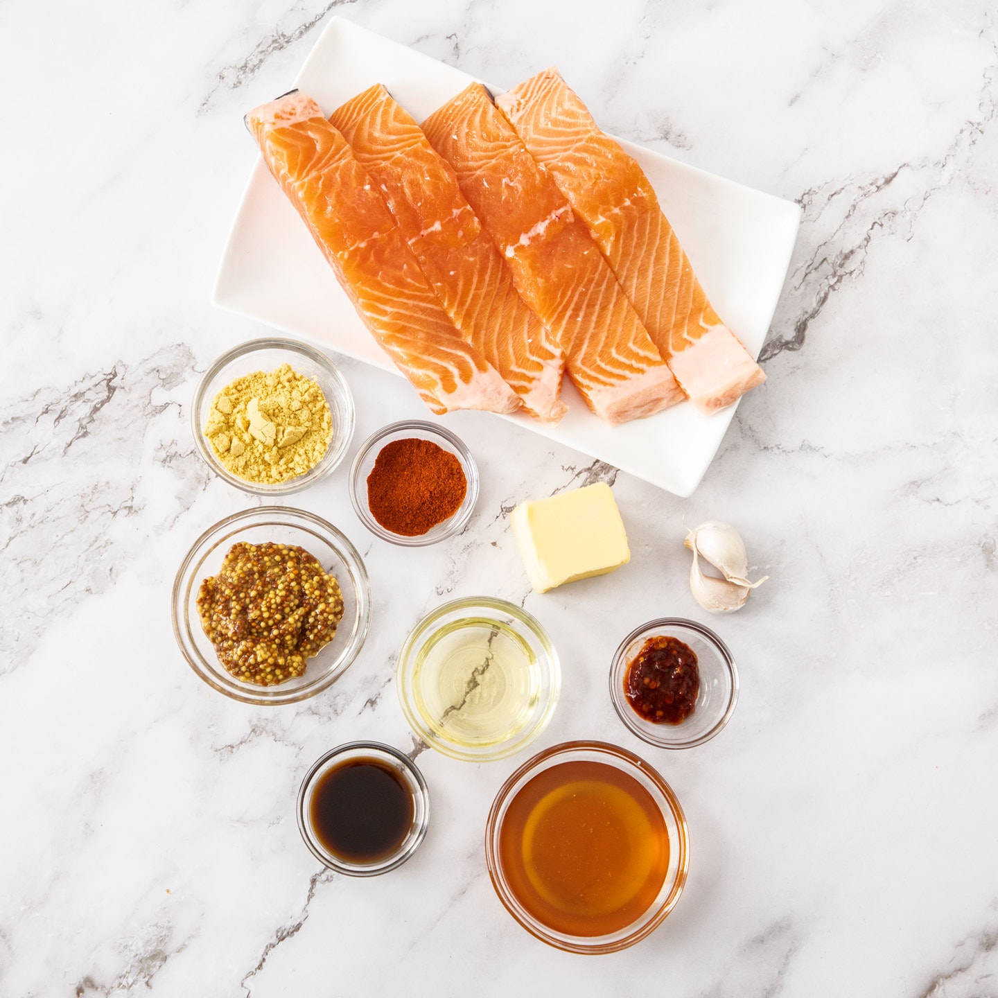 Ingredients for honey mustard salmon on a marble benchtop.