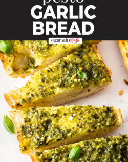 Slices of pesto garlic bread on a sheet of baking paper.