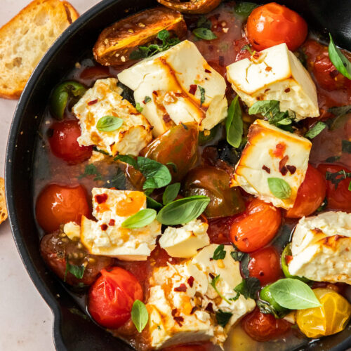 A cast iron skillet filled with baked feta and tomatoes.