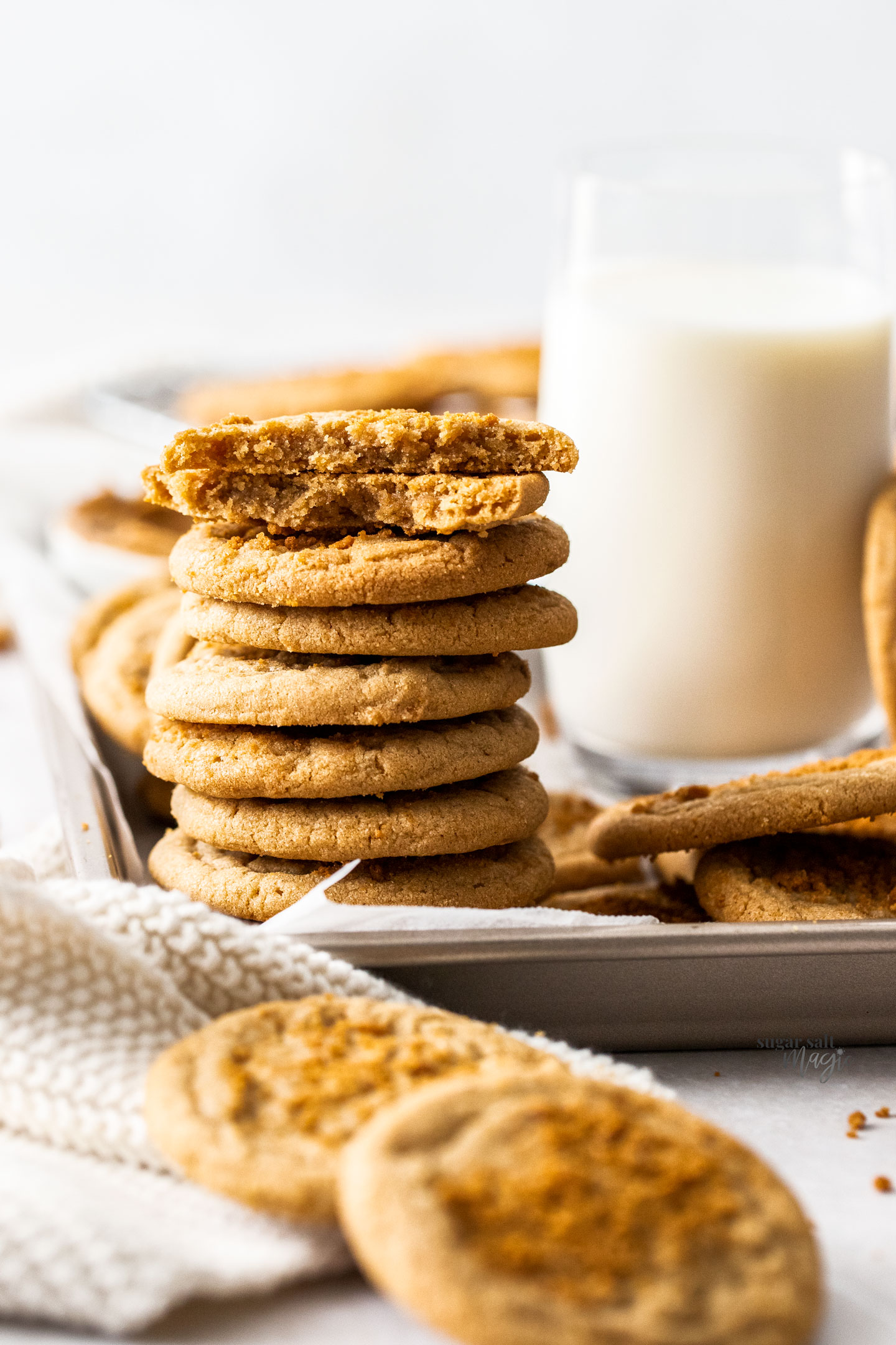 A stack of Biscoff butter cookies next to a glass of milk.