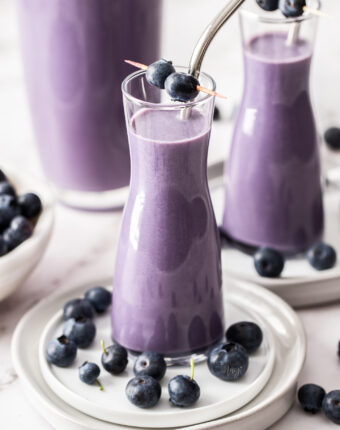 Two tall glasses filled with blueberry milk.