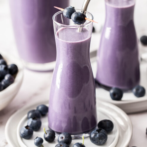 Two tall glasses filled with blueberry milk.