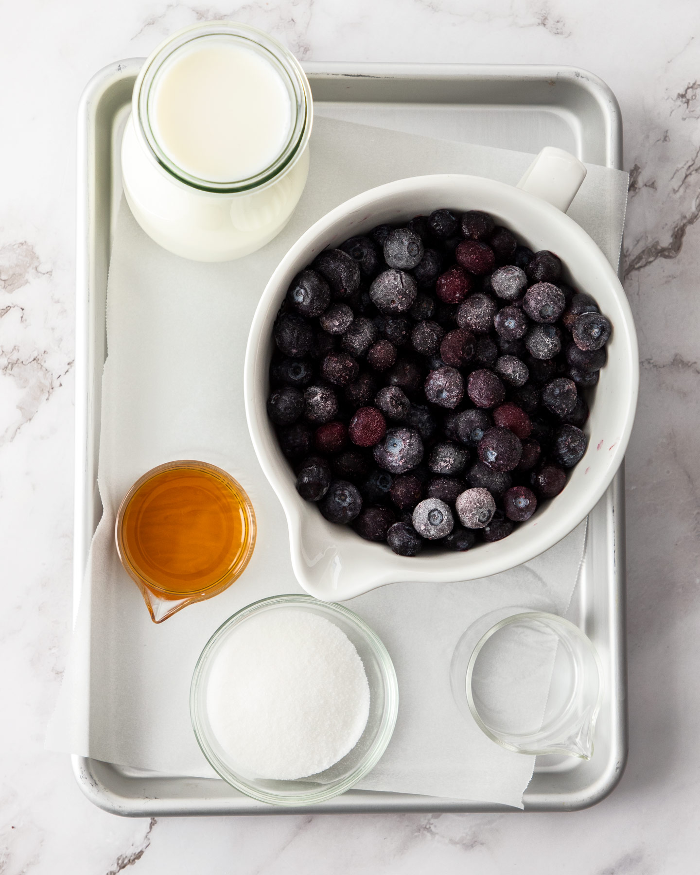 Ingredients for blueberry milk on a baking tray.