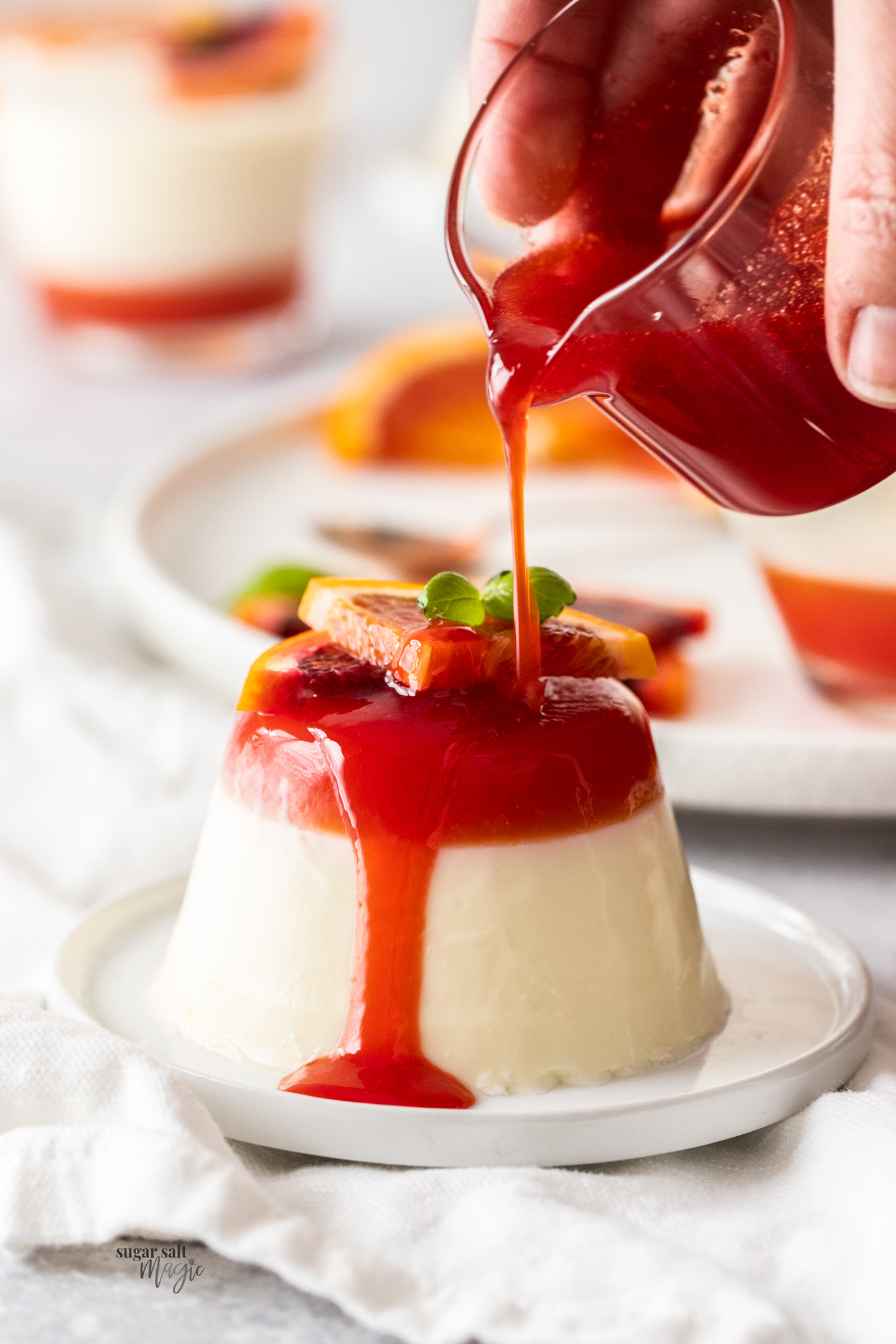Blood orange syrup being poured over a buttermilk panna cotta.